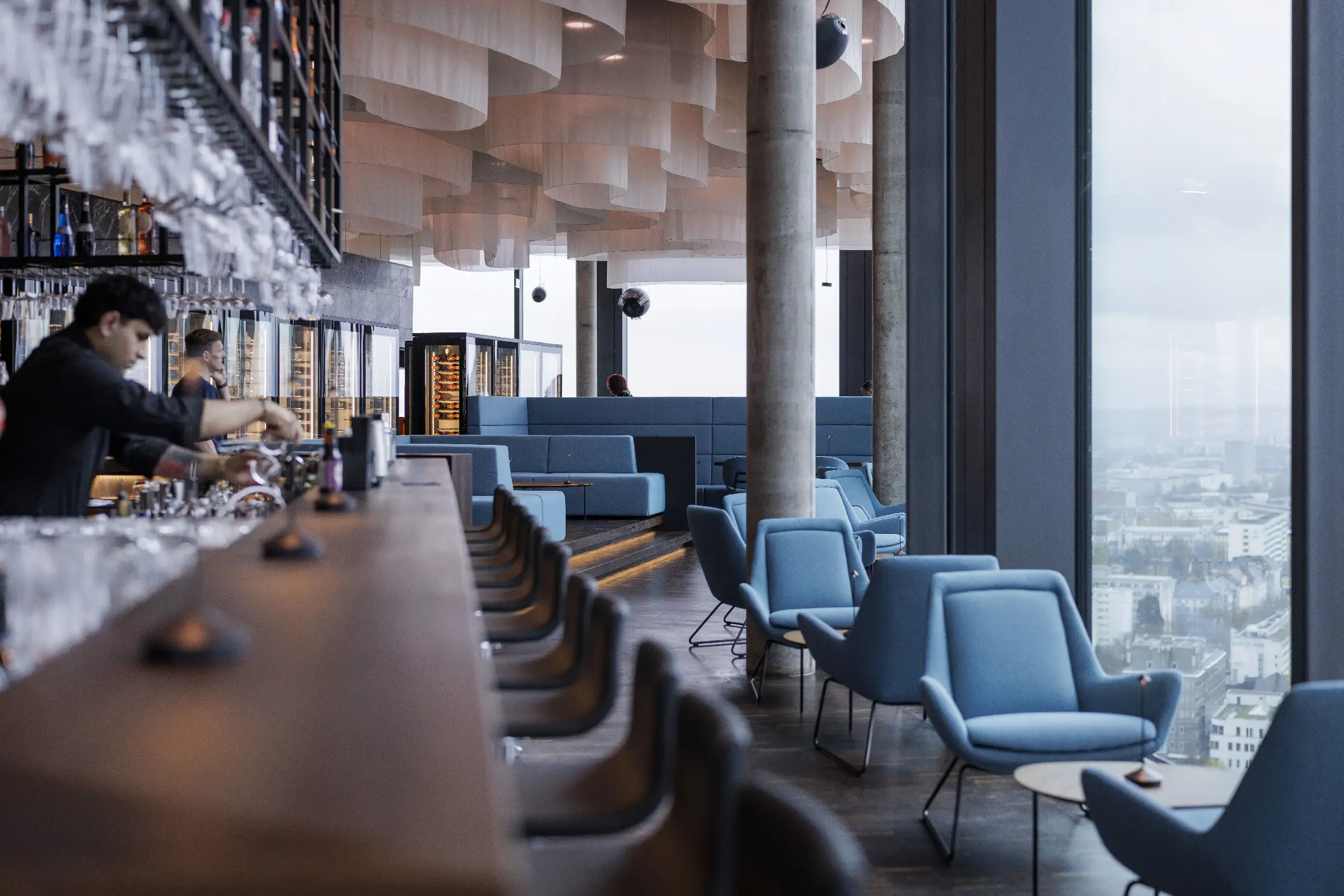Moderne Bar mit Blick auf die Stadt im Q27 Restaurant, stilvolle Sitzgelegenheiten und elegante Atmosphäre.