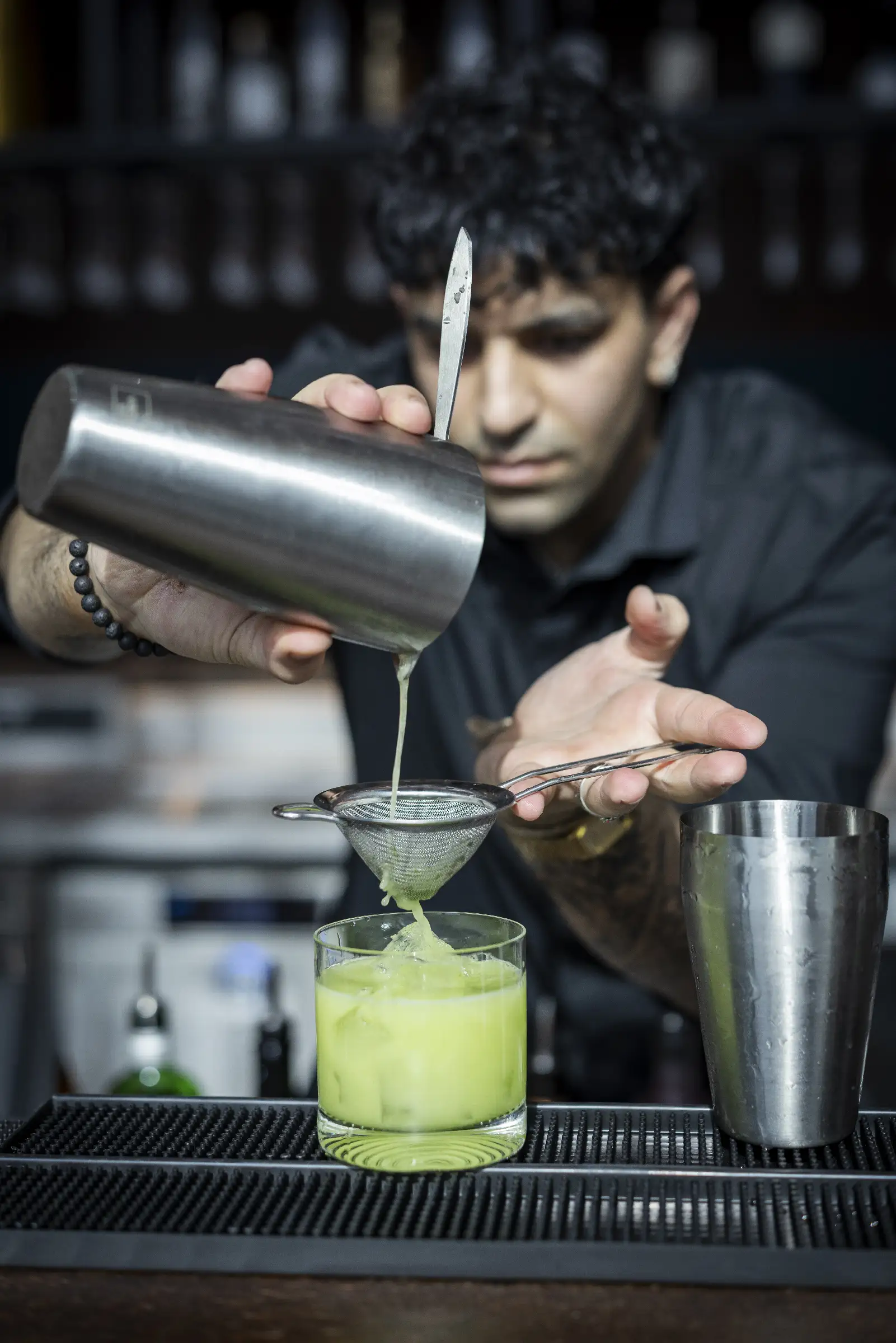 Cocktail wird durch ein Sieb in ein Glas gegossen, frisch zubereitet an der Bar.