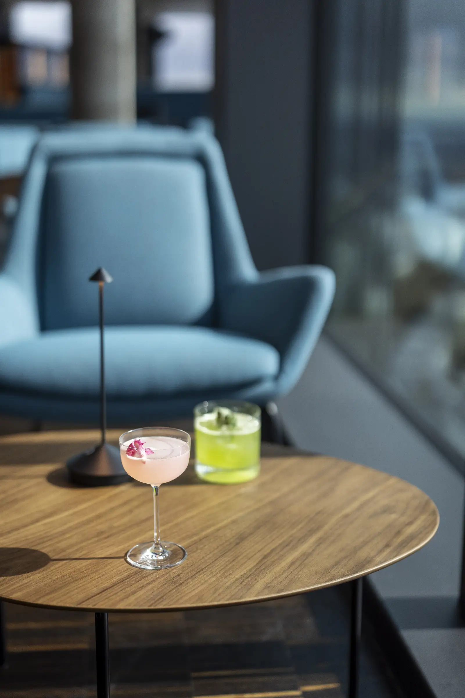 Zwei Cocktails auf einem Holztisch im Restaurant Q27, einer mit Blüten und einer in grün.