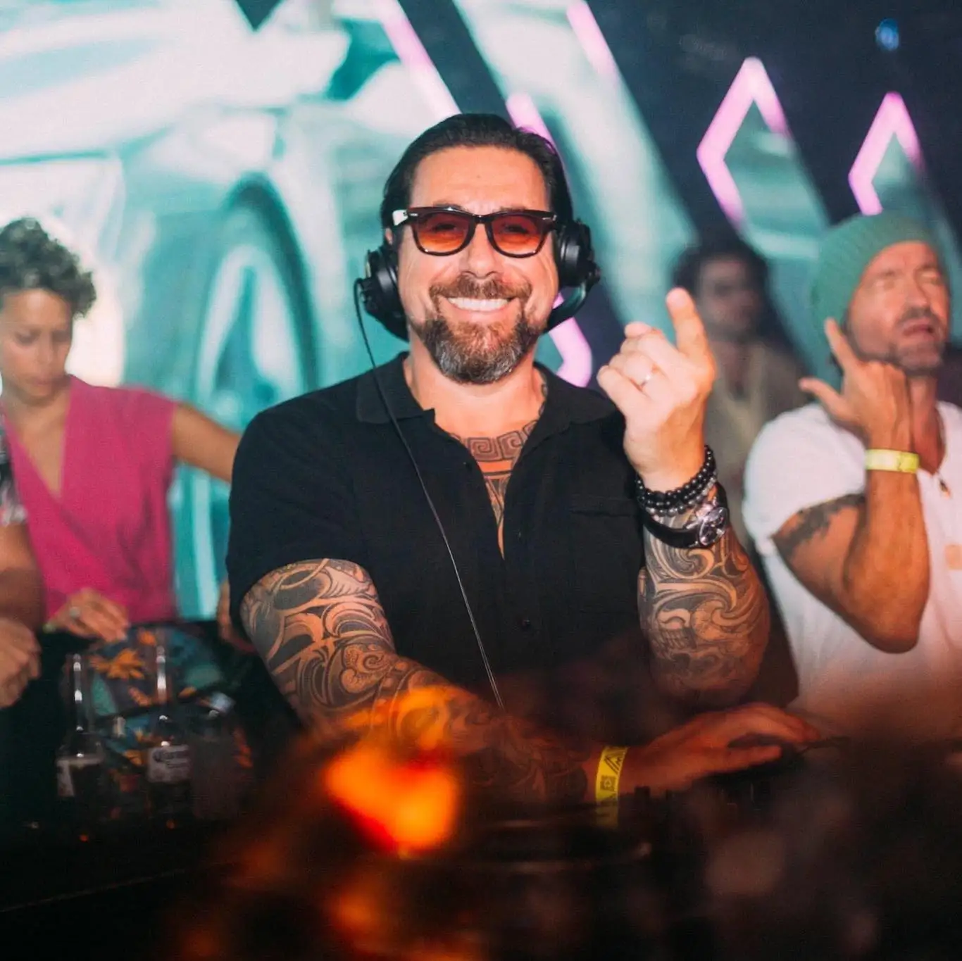 DJ an der Bar im Q27 mit bunten Lichtern und tanzenden Gästen im Hintergrund.