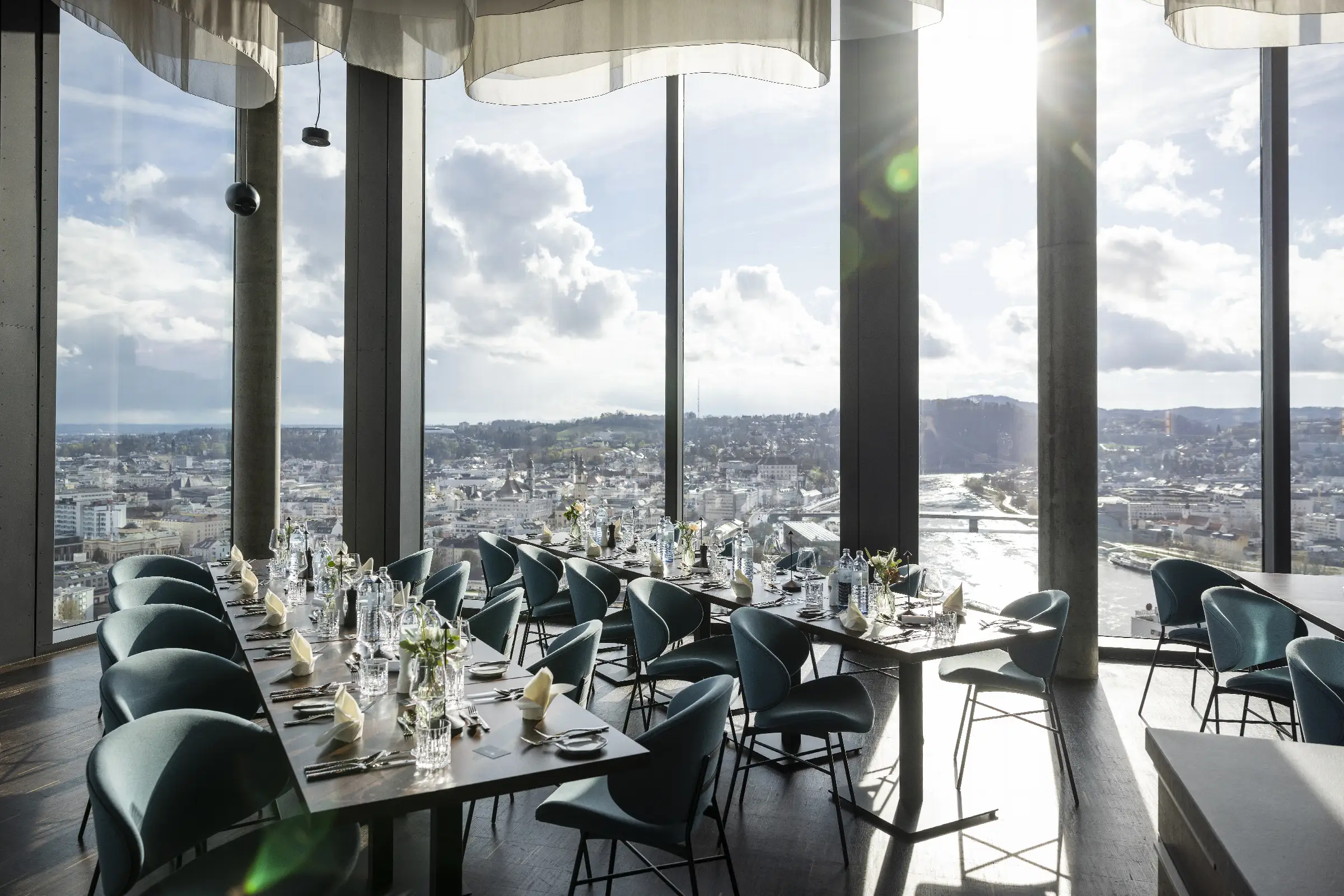 Eleganter Gastraum mit Blick auf die Stadt und den Fluss, stilvoll gedeckte Tische.