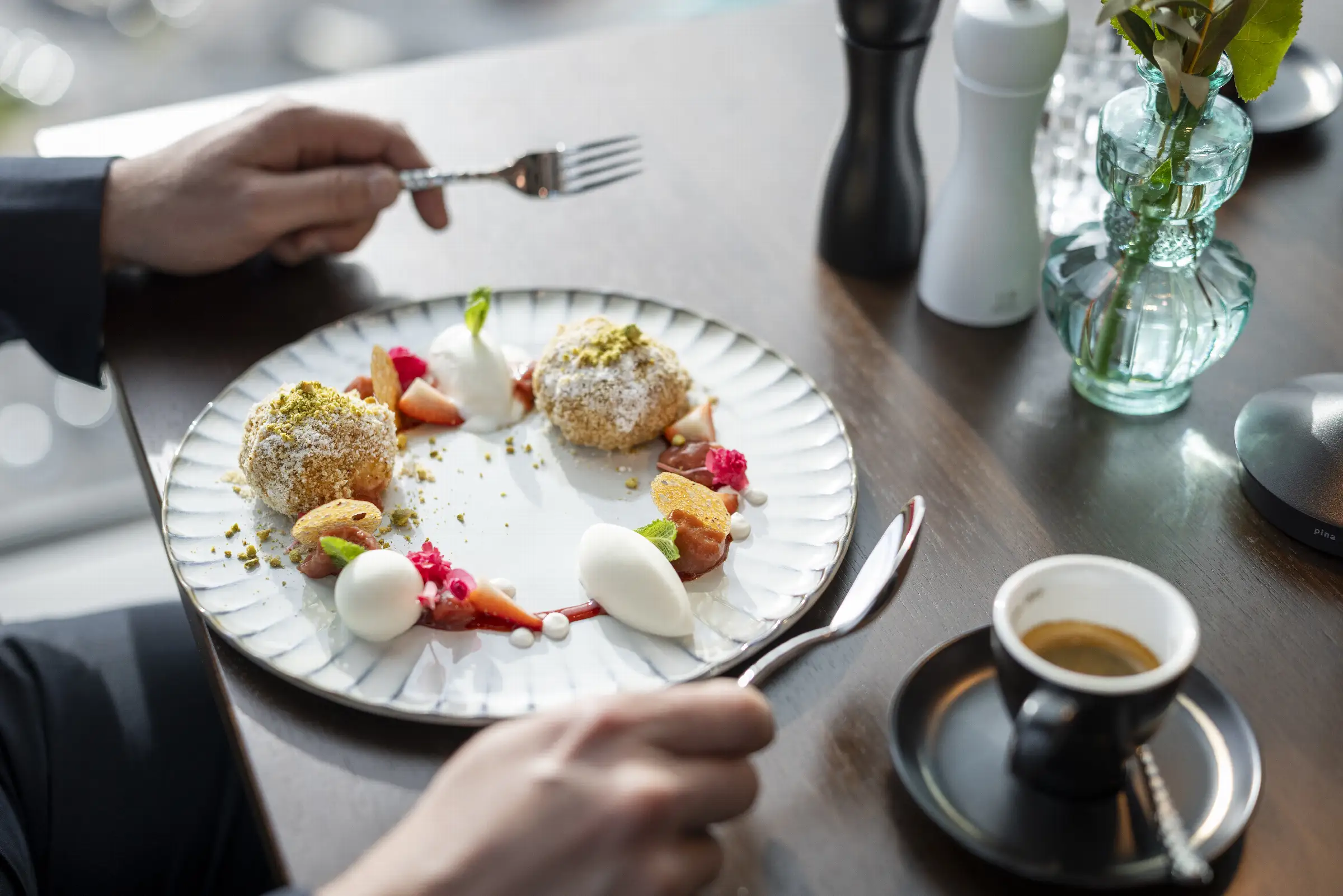 Köstliches Dessert mit frittierten Bällchen, frischen Früchten und Eiscreme auf einem eleganten Teller im Restaurant.