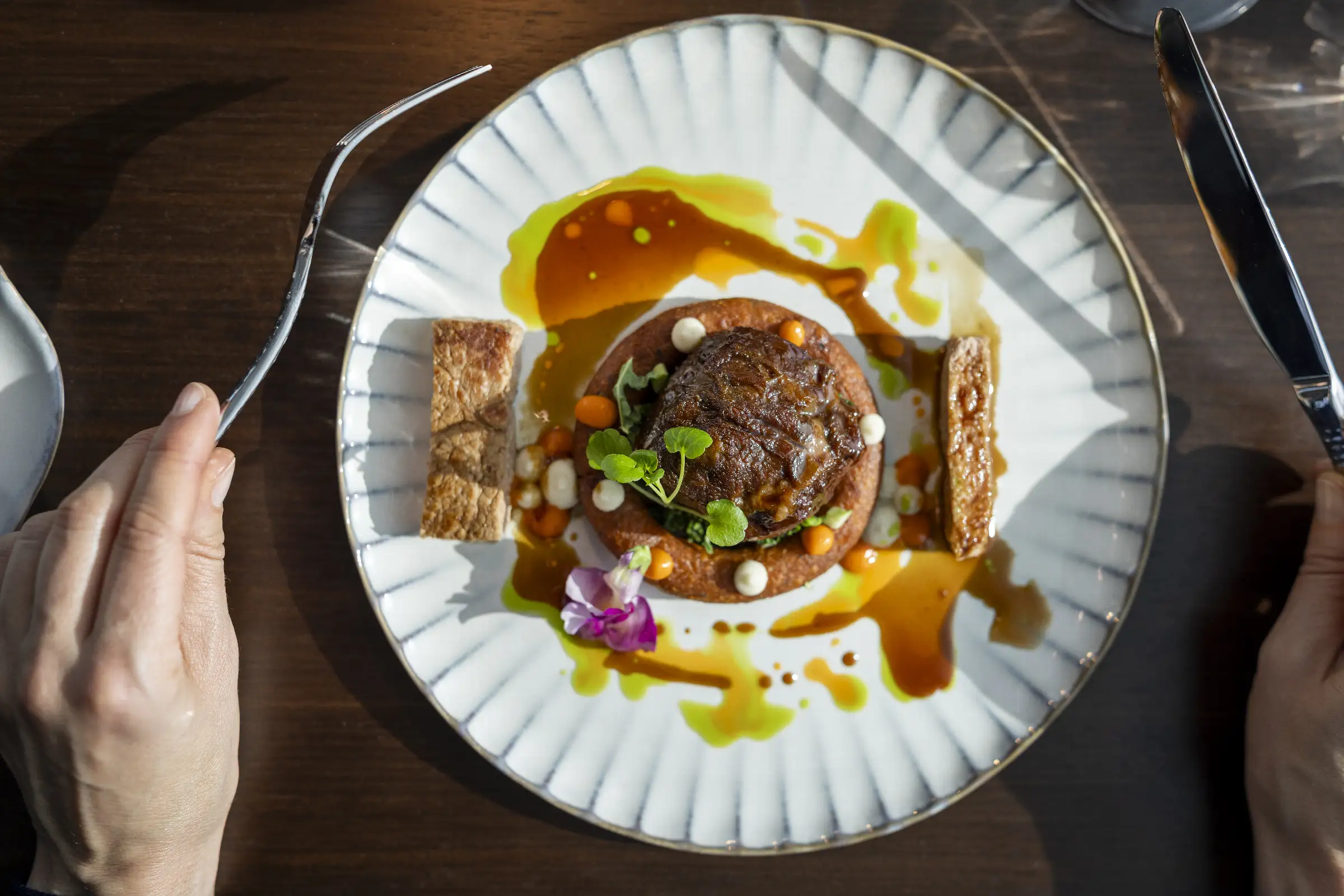 Zartes Rindfleisch auf einem Teller mit Gemüse, Sauce und Beilagen im Restaurant Q27